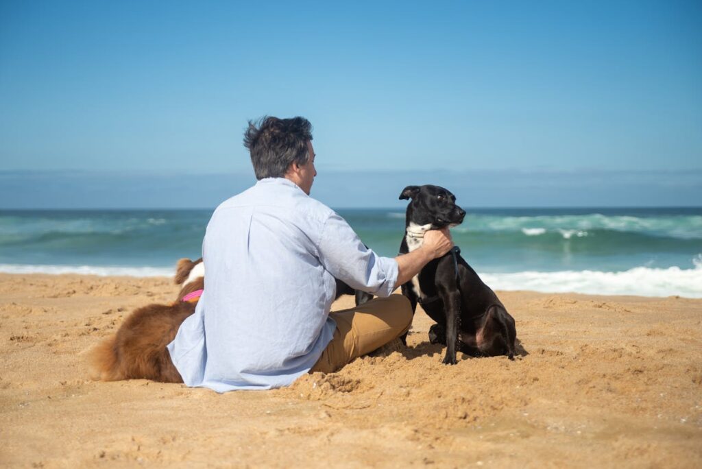 Cane nero in riva al mare accanto al padrone, momento di complicità e comunicazione non verbale