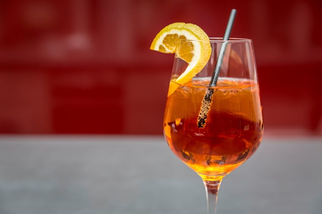 Bicchiere di spritz con cannuccia e fetta di limone, rappresentazione dei rischi dell’alcol per i cani.