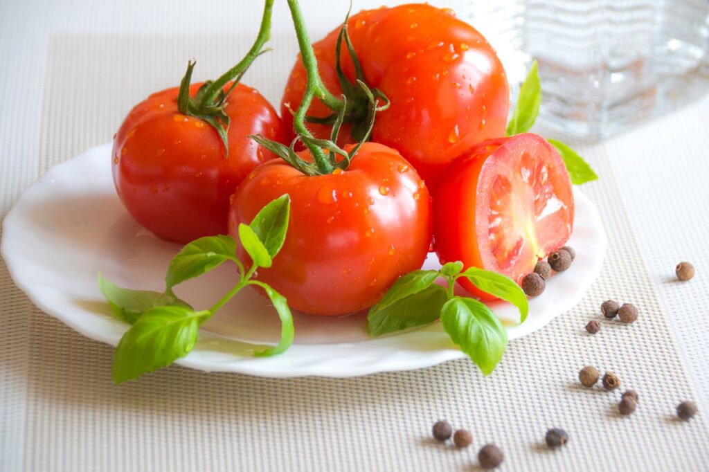 Pomodori appoggiati su un piatto bianco, ortaggio non consigliato nella dieta dei cani.
