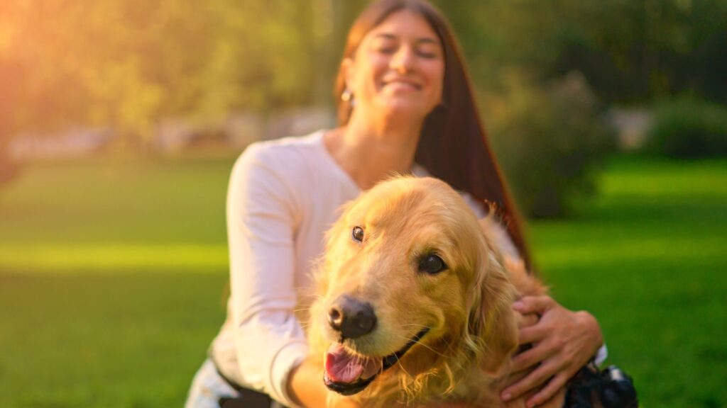 Psicologia del cane: coccole e affetto, ragazza che coccola il suo cane in un prato rispettando il suo linguaggio del corpo