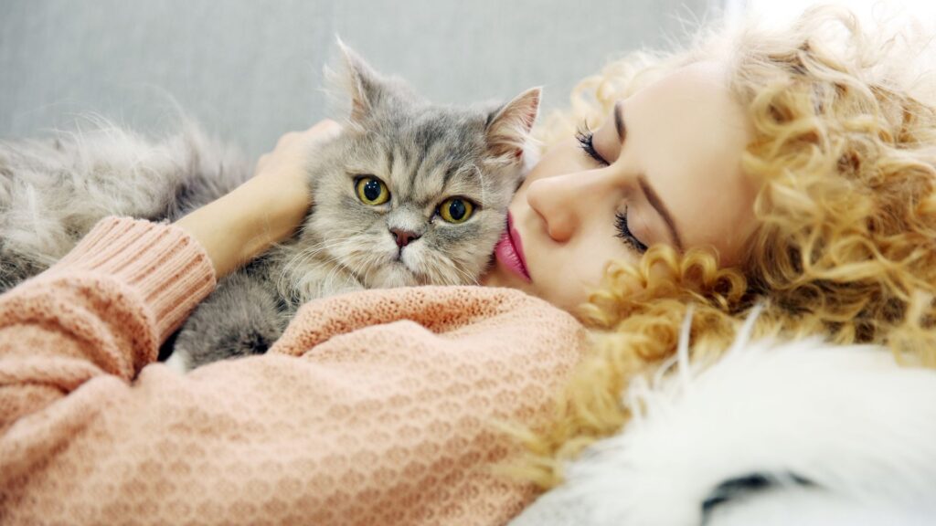Donna sdraiata che coccola il suo gatto in un momento di affetto e relax